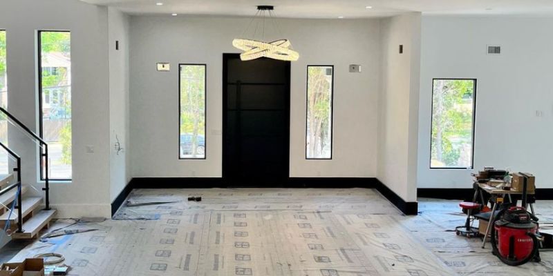 Spacious modern home interior with custom lighting installation, recessed lights, and contemporary chandelier setup in progress.