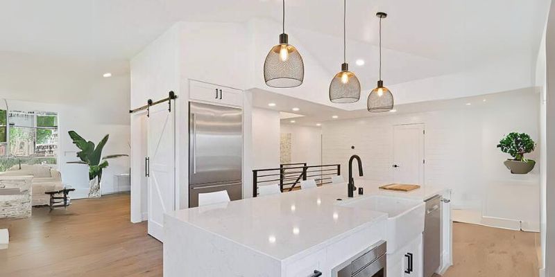 Modern residential kitchen with pendant lighting and custom electrical fixtures in a bright open-concept home.